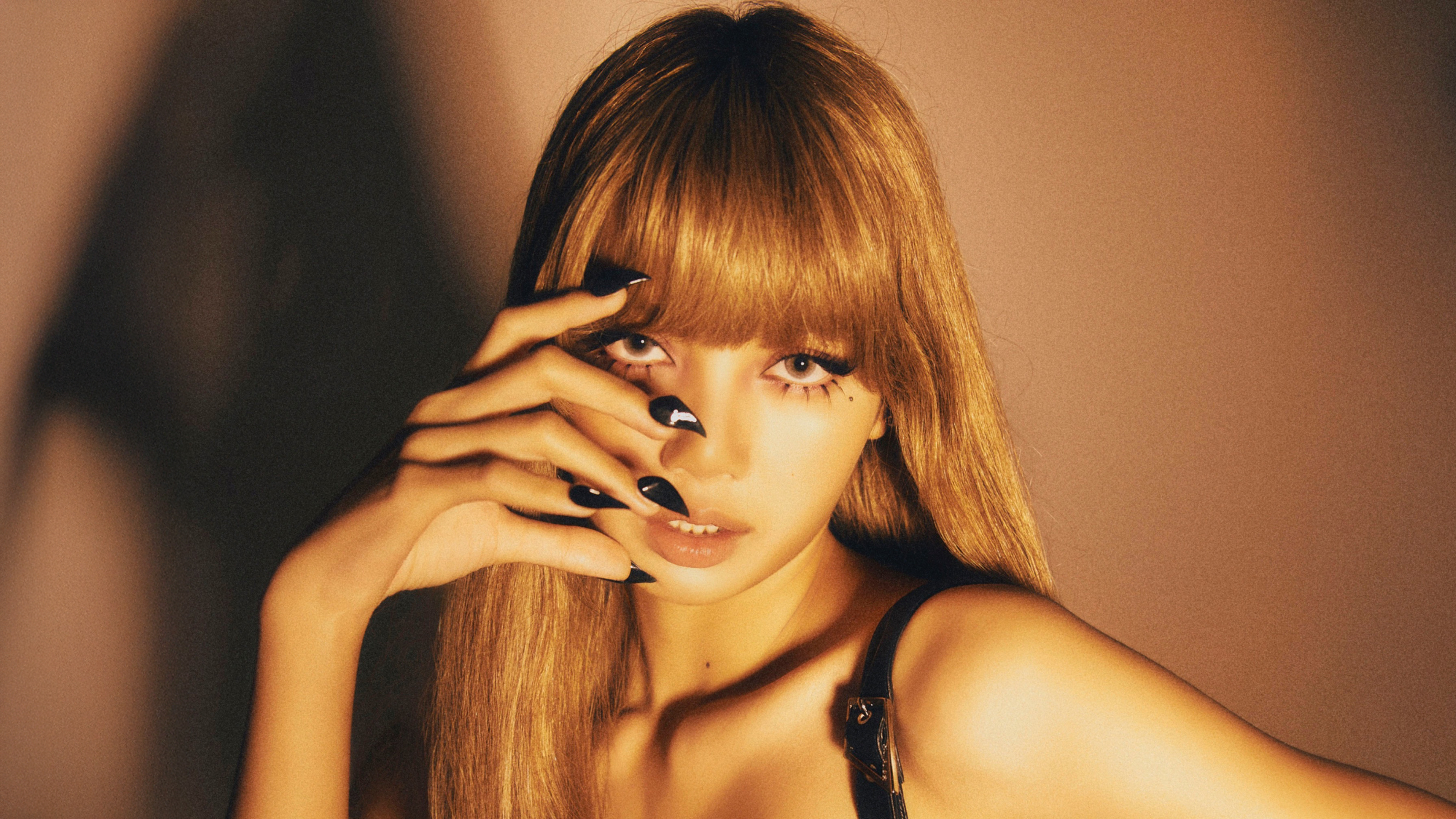A solo portrait of Lisa from BLACKPINK featuring a warm brown aesthetic and soft lighting