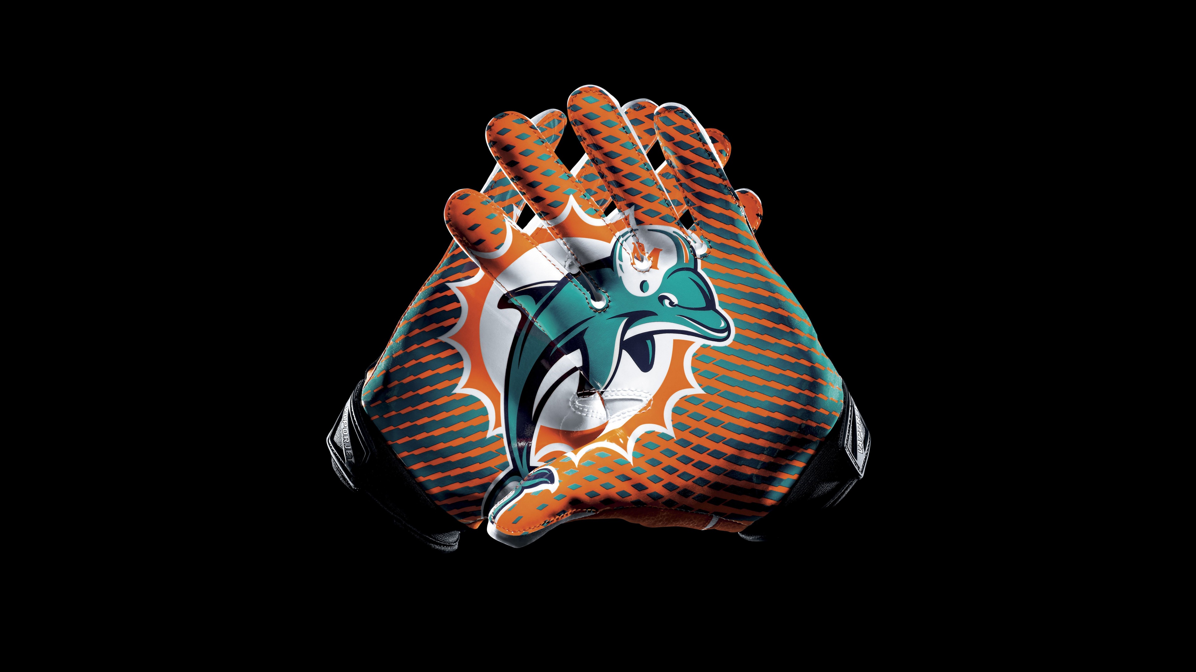 A close-up shot of Miami Dolphins themed football gloves on a solid black background.