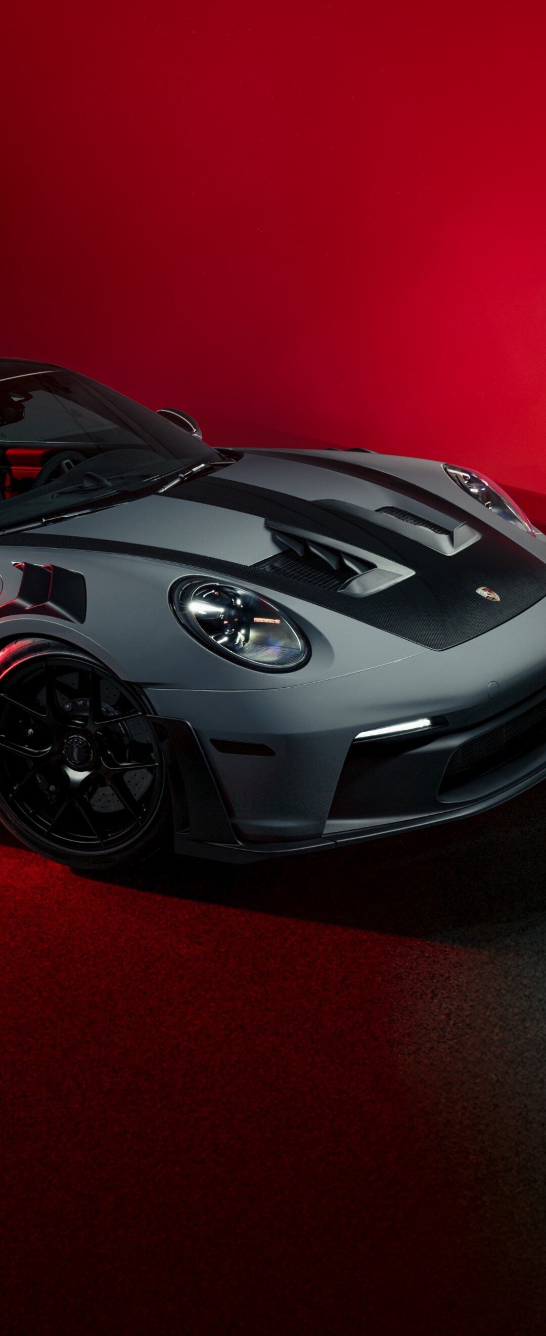 A sleek and powerful Porsche 911 GT3 RS sports car presented against a bold, vibrant red background.