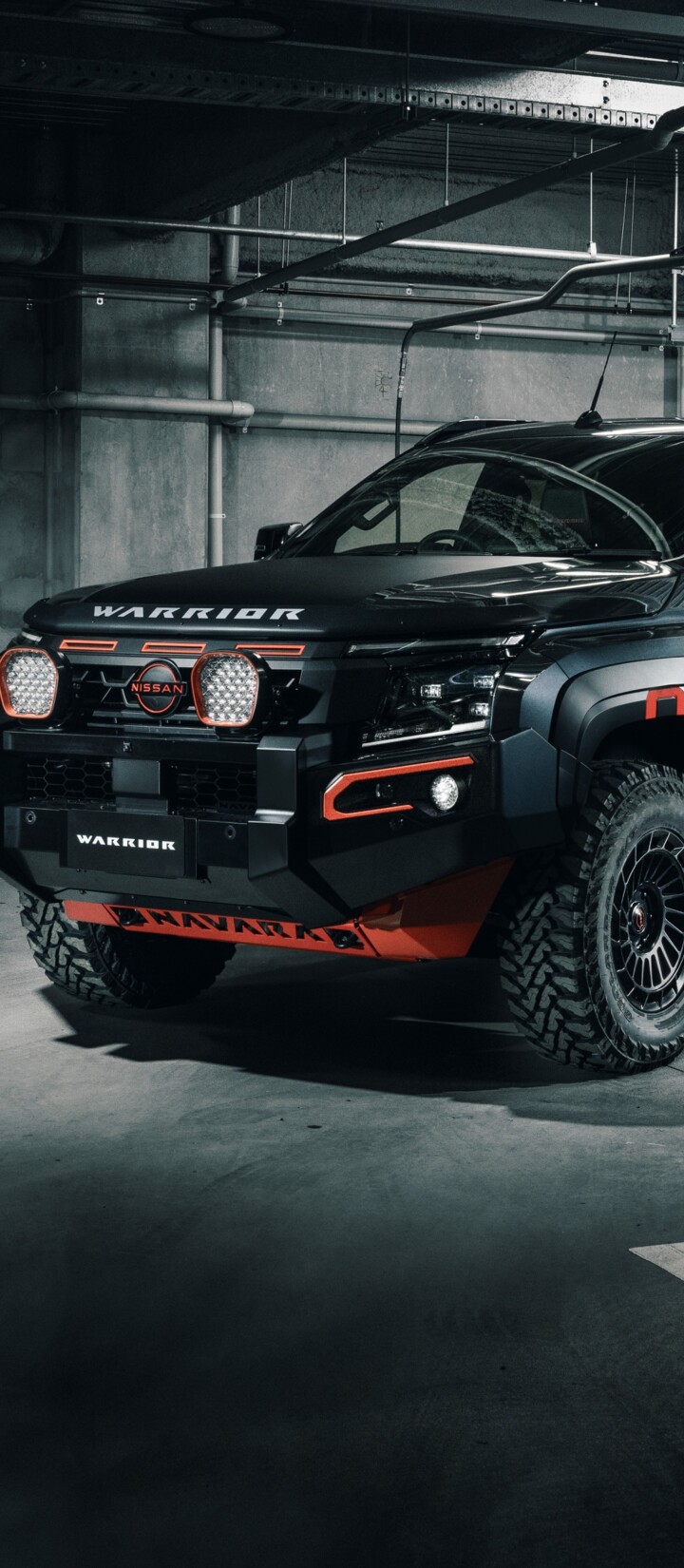 A matte black rugged off-road pickup truck parked in a dimly lit parking garage.