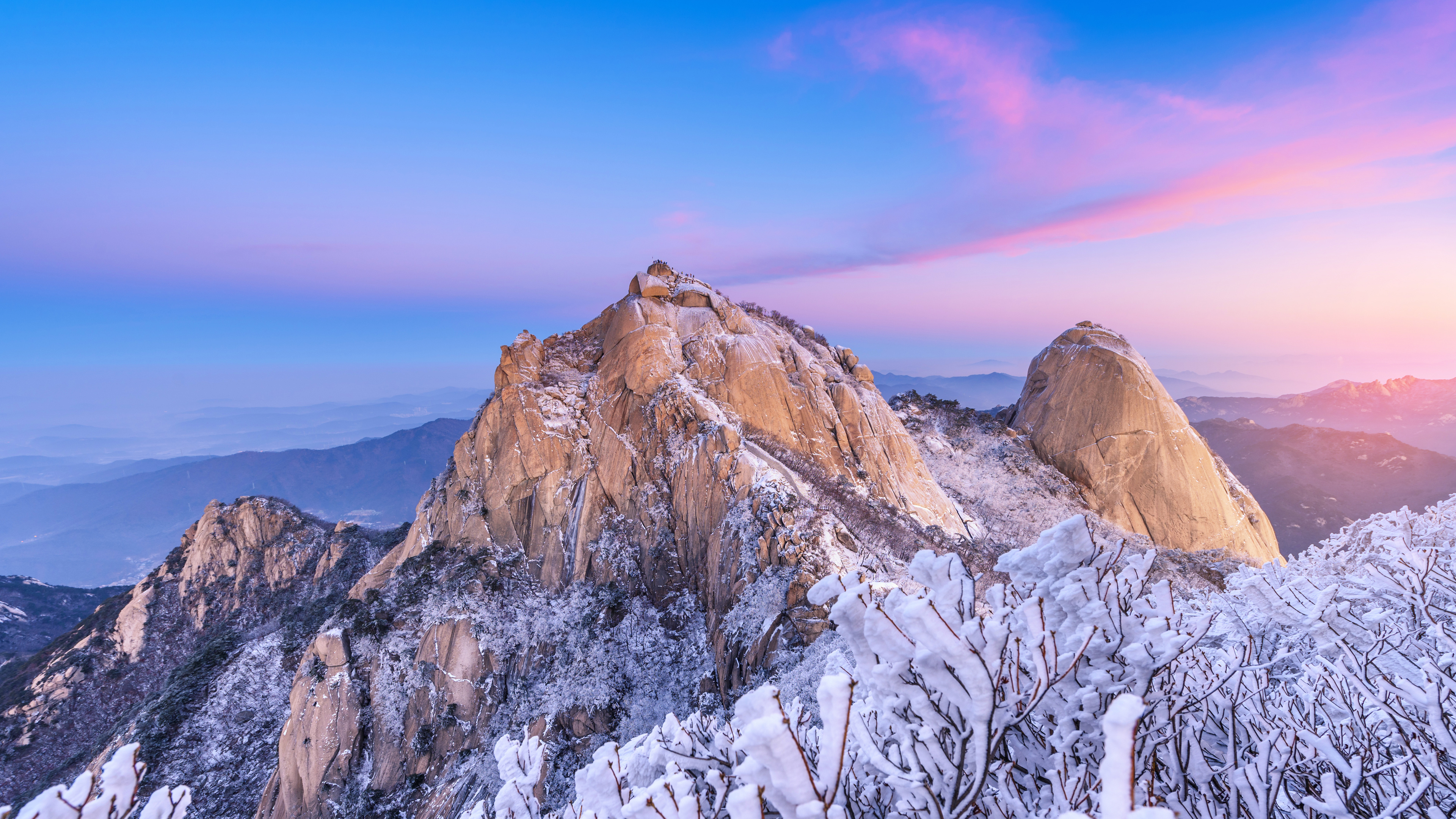 A beautiful view of a snow-covered mountain peak in Seoul, South Korea, featuring frozen trees and a serene winter morning atmosphere.