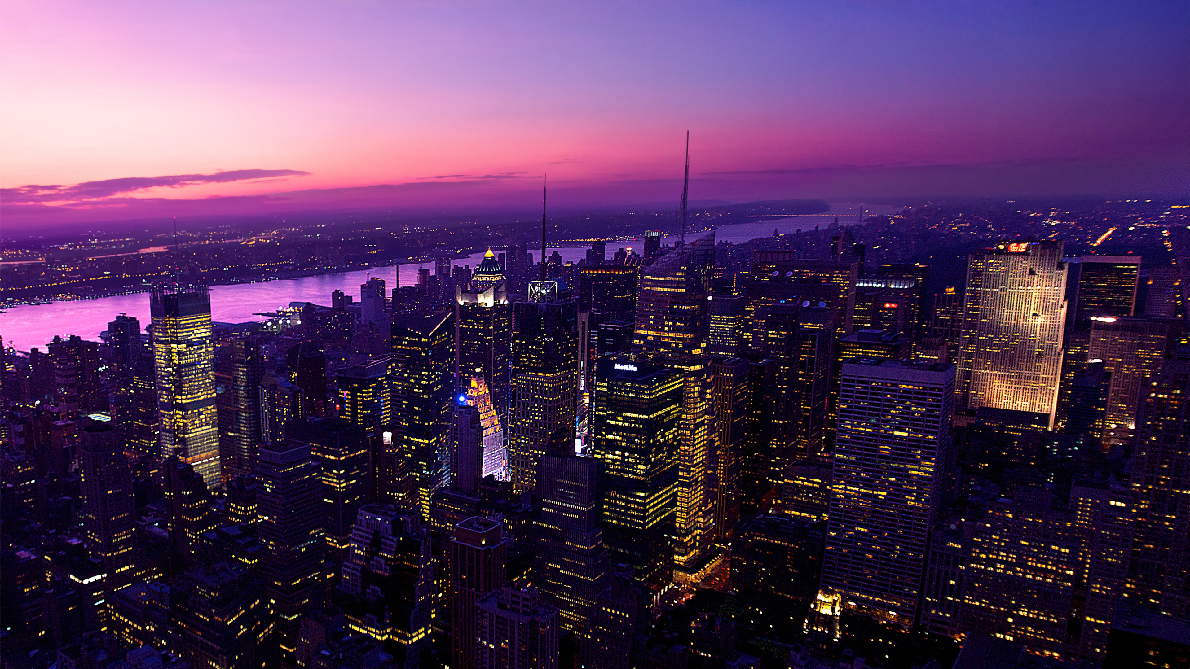 An aesthetic evening cityscape of the New York City skyline featuring a pink and purple twilight sky and glowing skyscrapers.